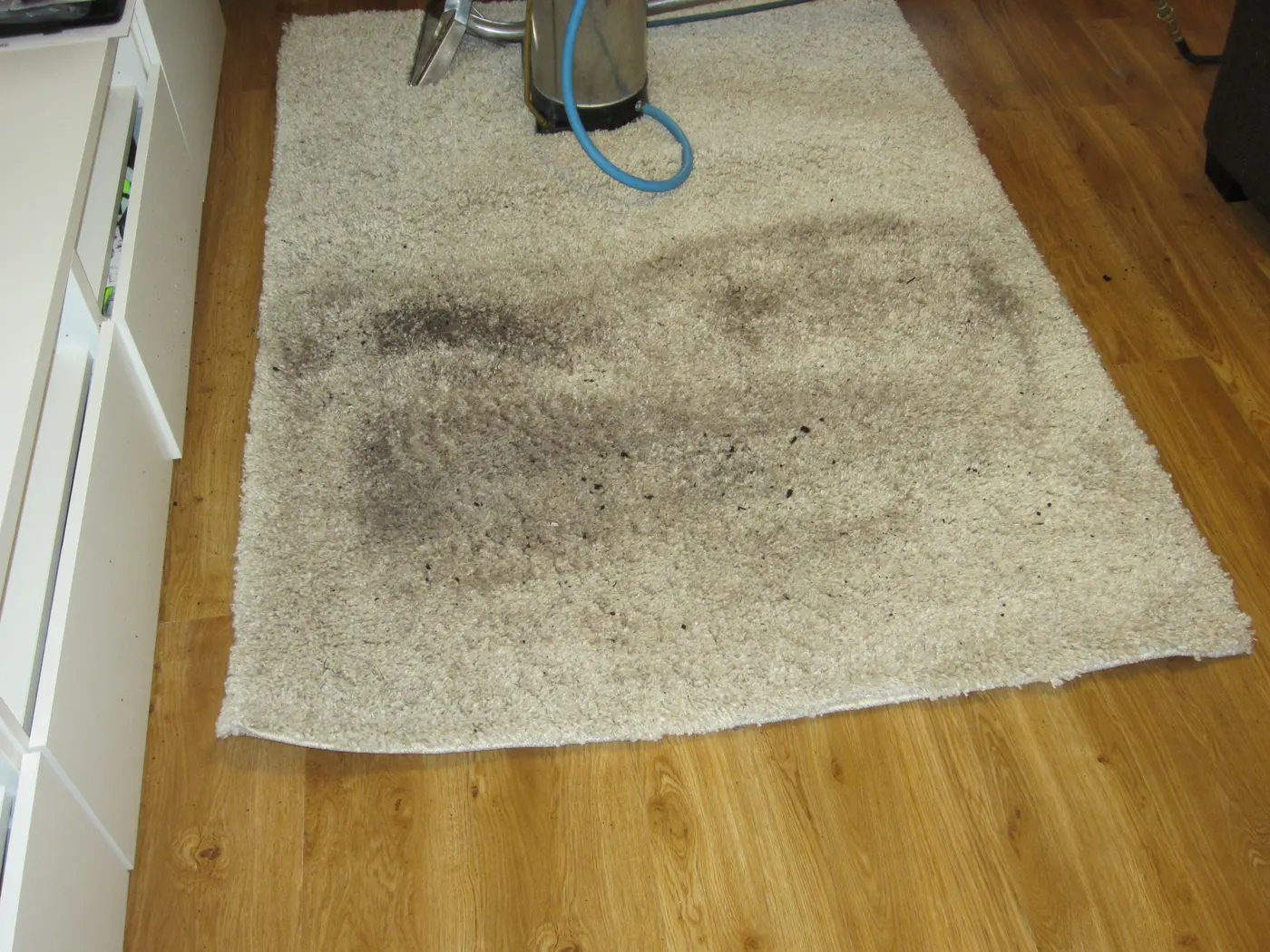 A cream rug before cleaning, heavily soiled across the middle